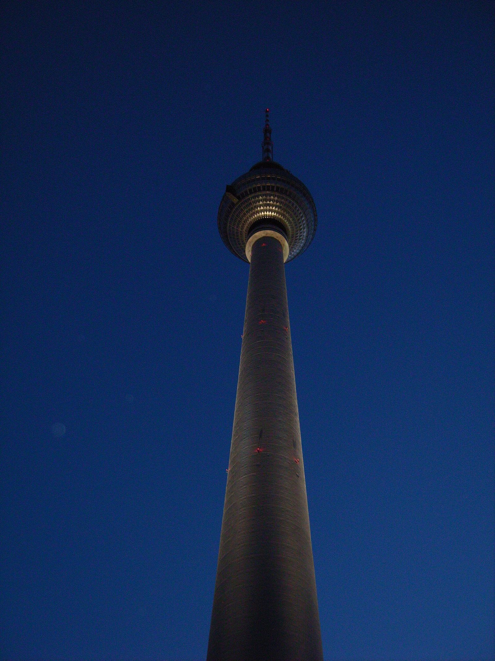 Der Schaft des Fernsehturms mit der Turmkugel, steil von unten fotografiert vor tiefblauem Himmel in der Dämmerung