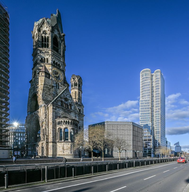 Die Turmruine der Kaiser-Wilhelm-Gedächtniskirche am Breitscheidplatz, daneben der achteckige Kirchenneubau von Egon Eiermann und ein modernes Hochhaus