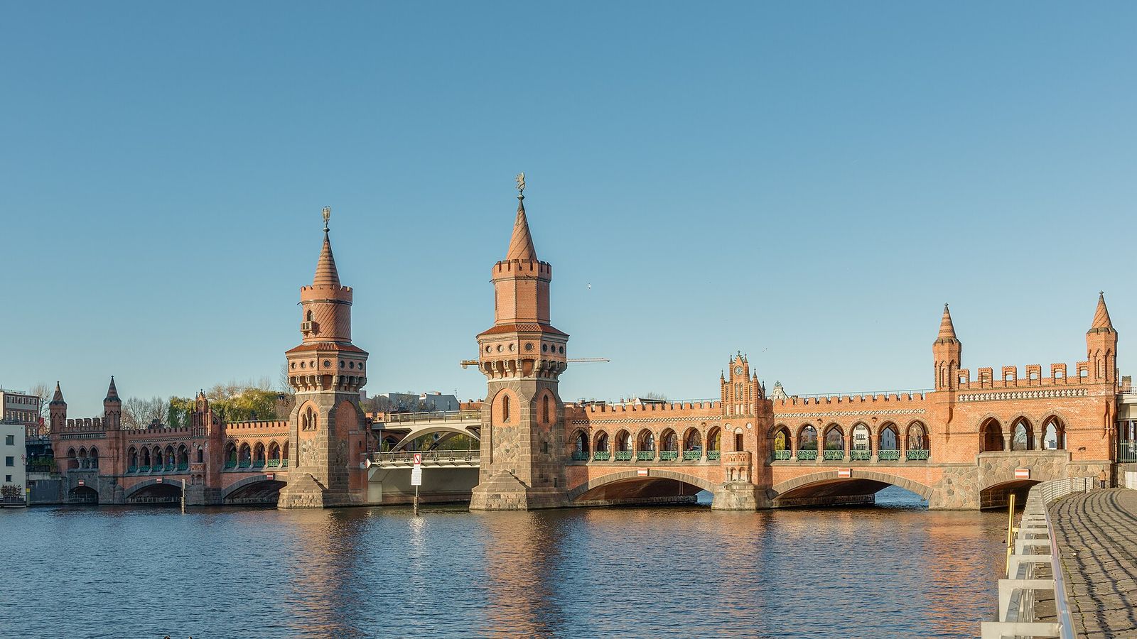 Die Oberbaumbrücke mit ihren zwei Backsteintürmen und Bogengängen über der Spree in warmem Licht